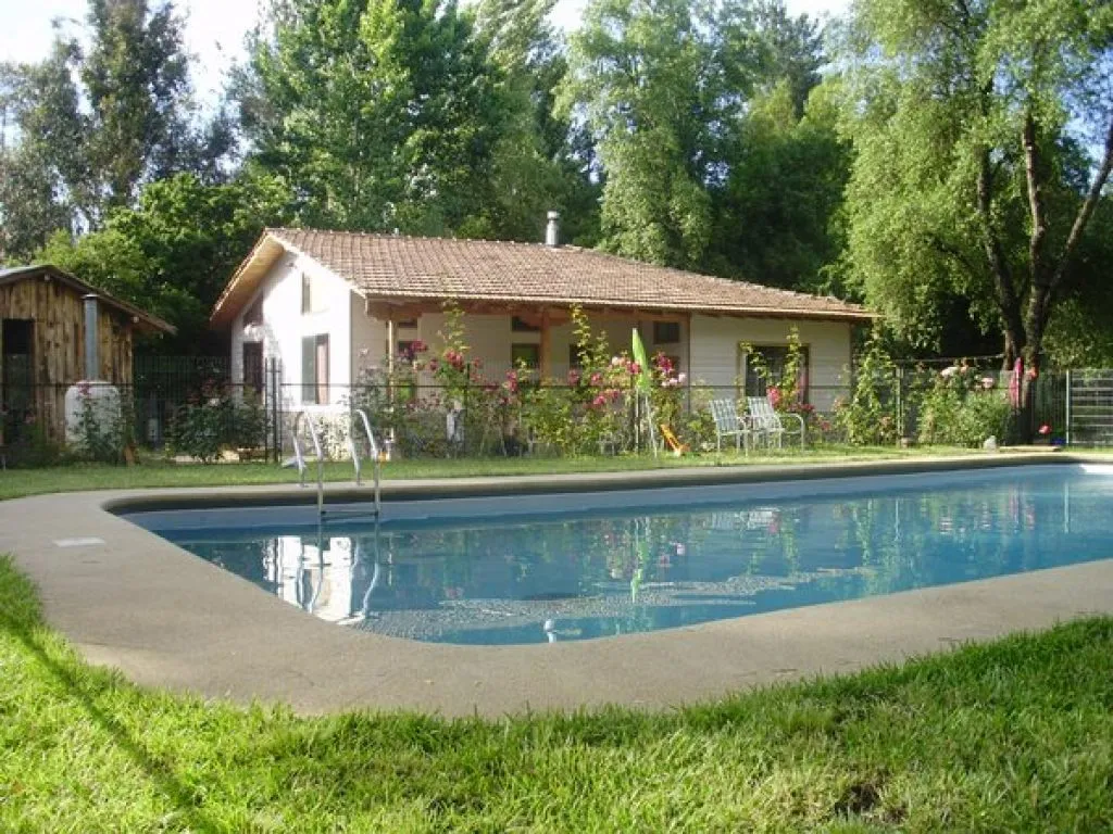 Vista exterior de Cabañas Los Arcos con piscina, jardín y cabaña entre árboles en el Salto del Laja